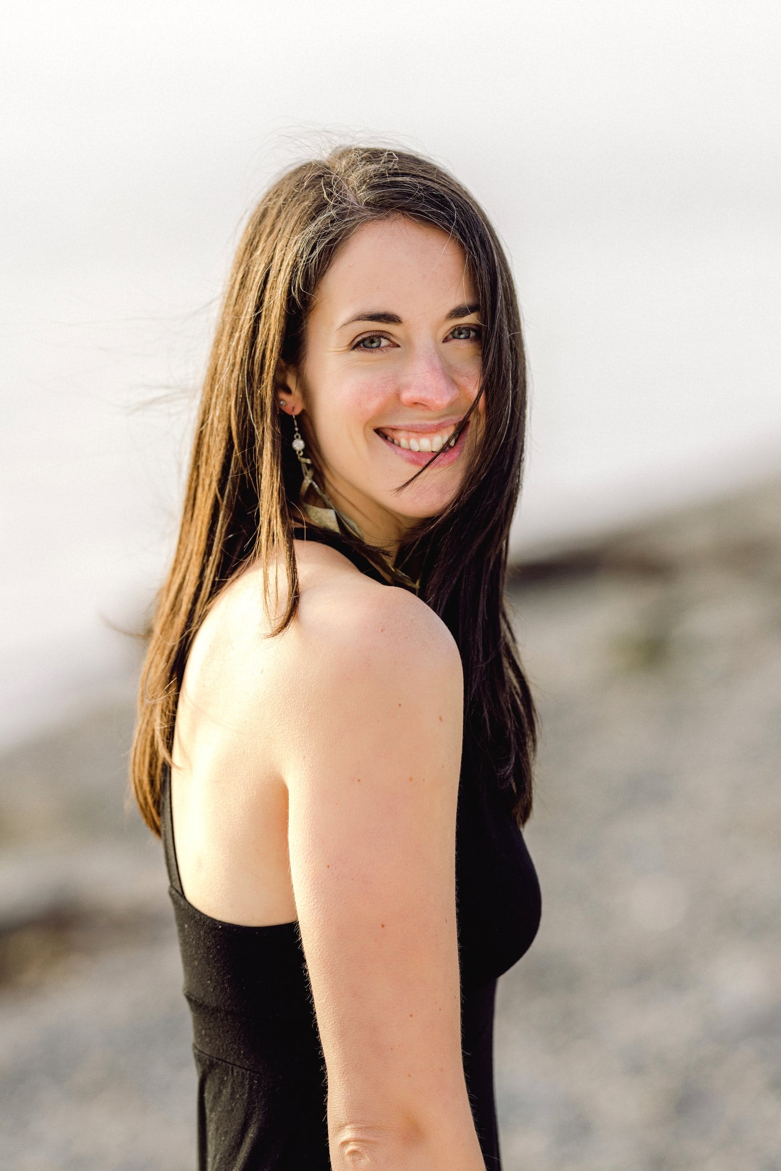 Woman in black glancing over her shoulder at the beach