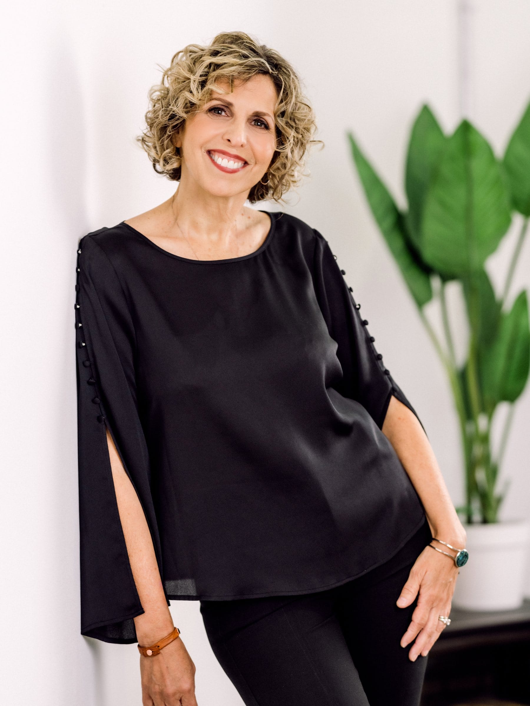 Woman with short curls in a black cape-sleeve top
