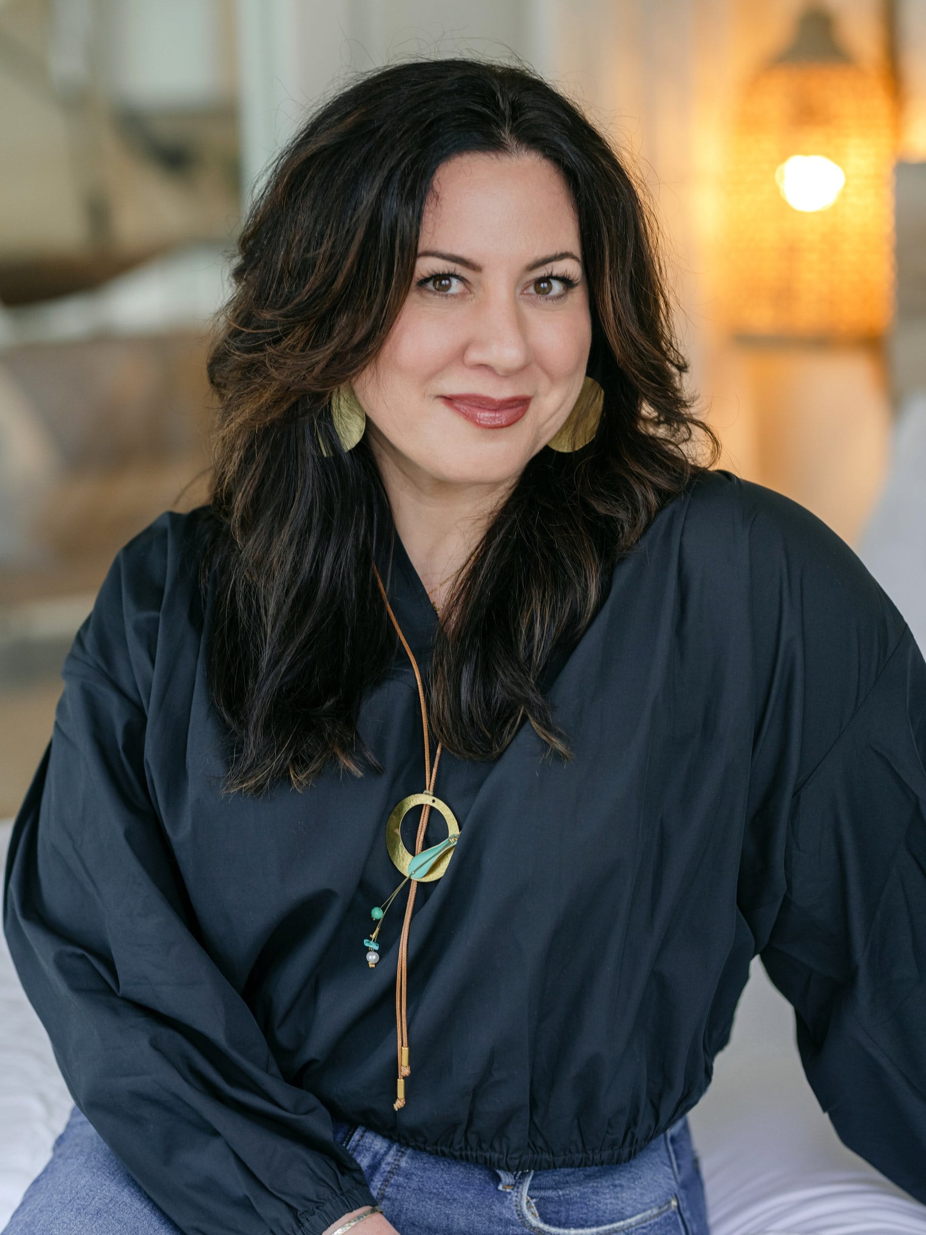 Woman in a navy blouse with a statement necklace in warm light