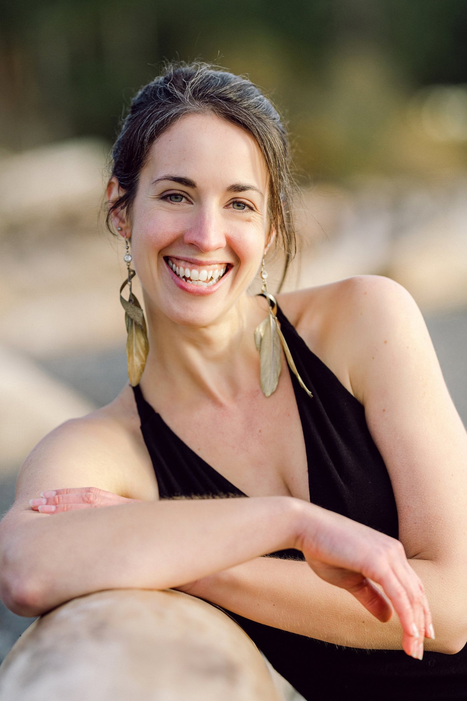 Laughing woman in black leaning on driftwood at the beach
