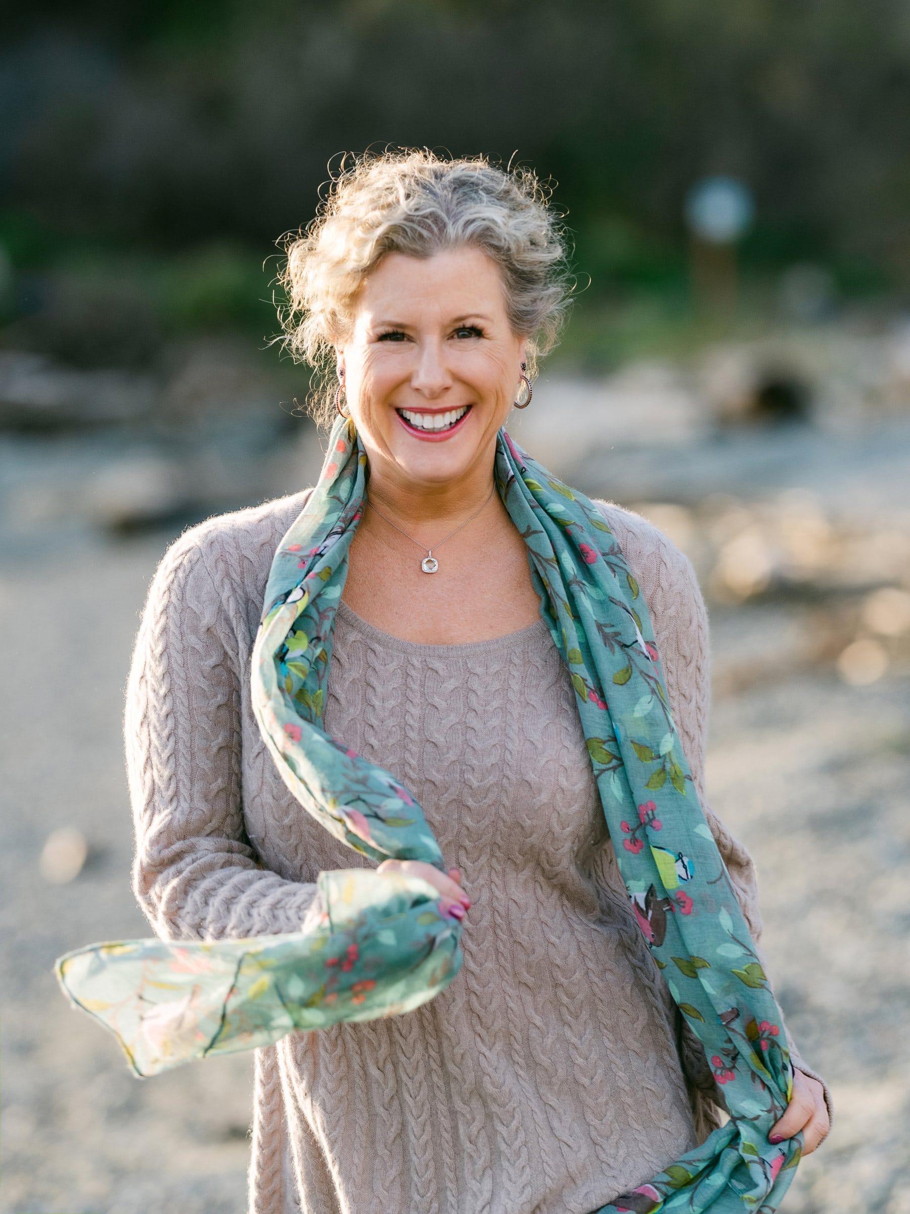 Silver-haired woman with a printed scarf on the beach