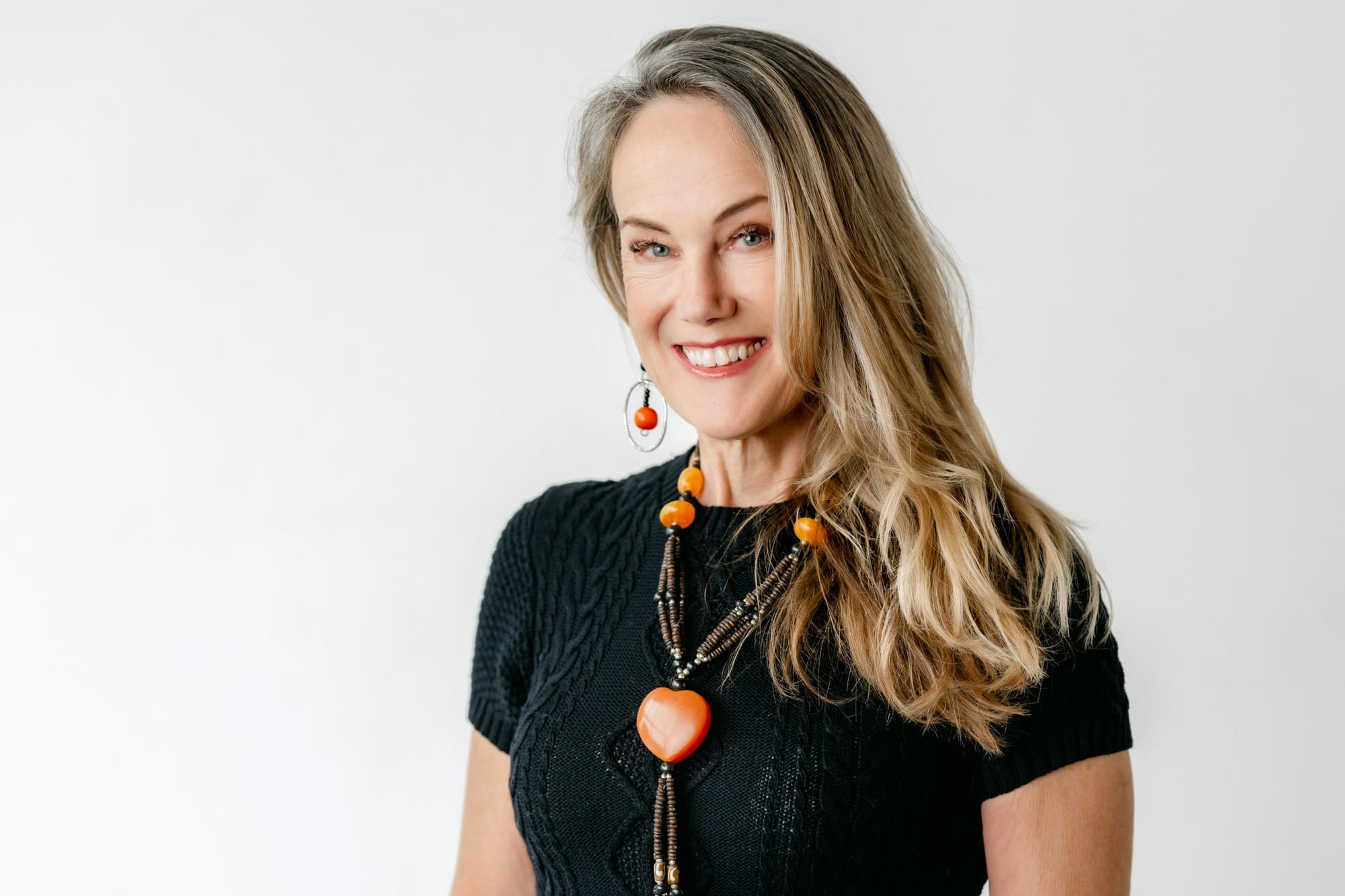 Woman with long hair and a statement necklace against a white wall