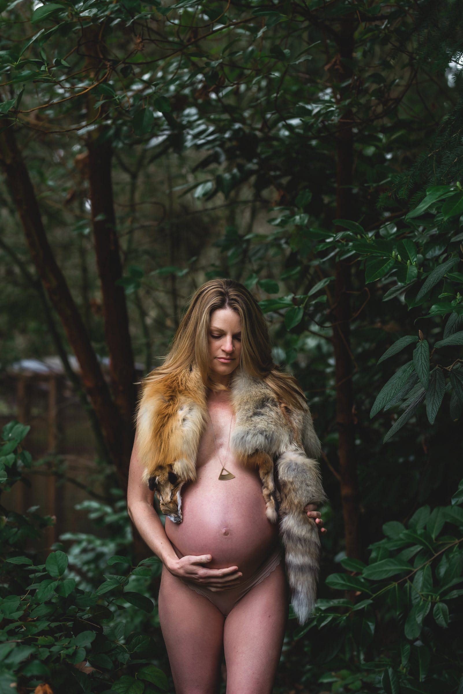 Expectant mother with a fox stole in a dark forest
