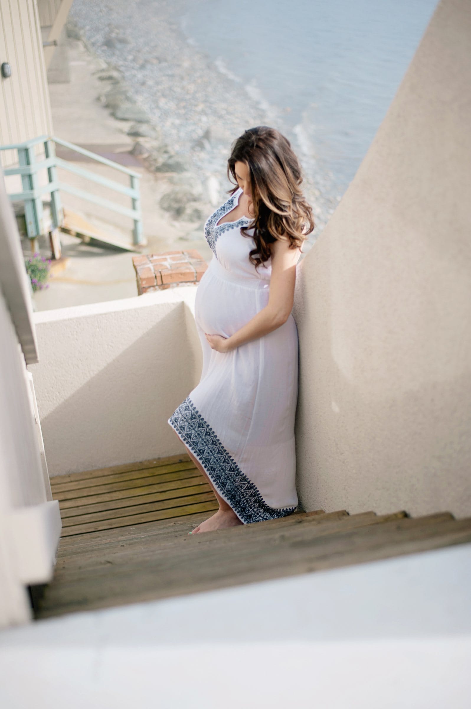 Expectant mother on the stairs of a beach house