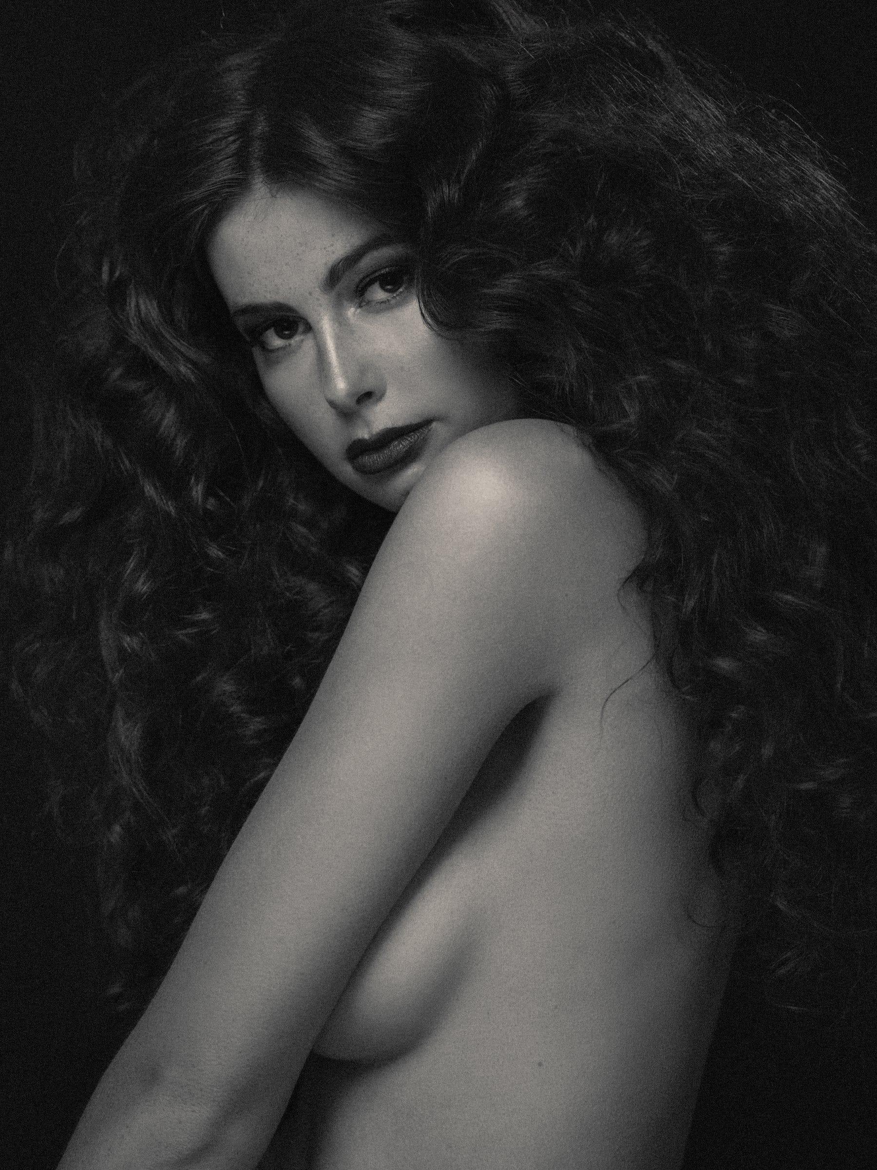 Black and white fine art portrait of a woman with curly hair