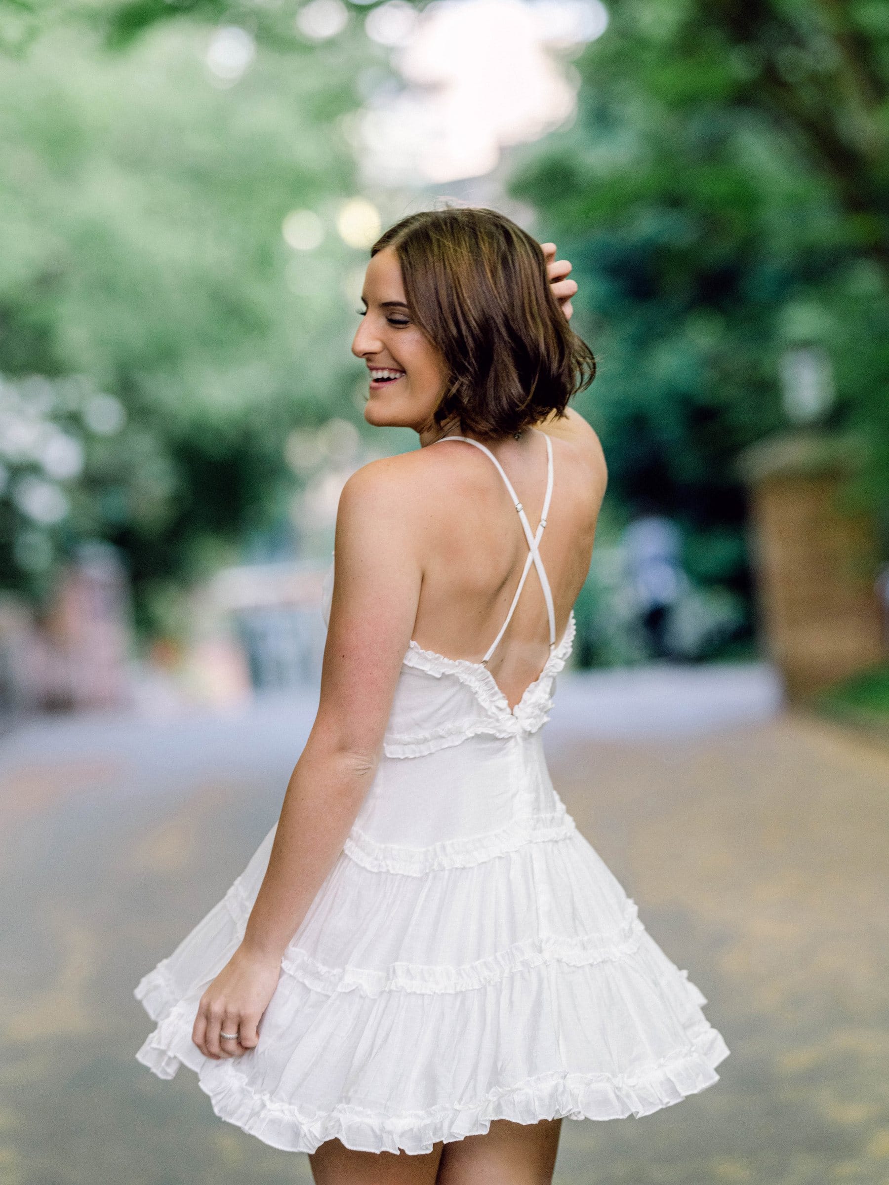 Young woman in a white dress glancing back on a garden path