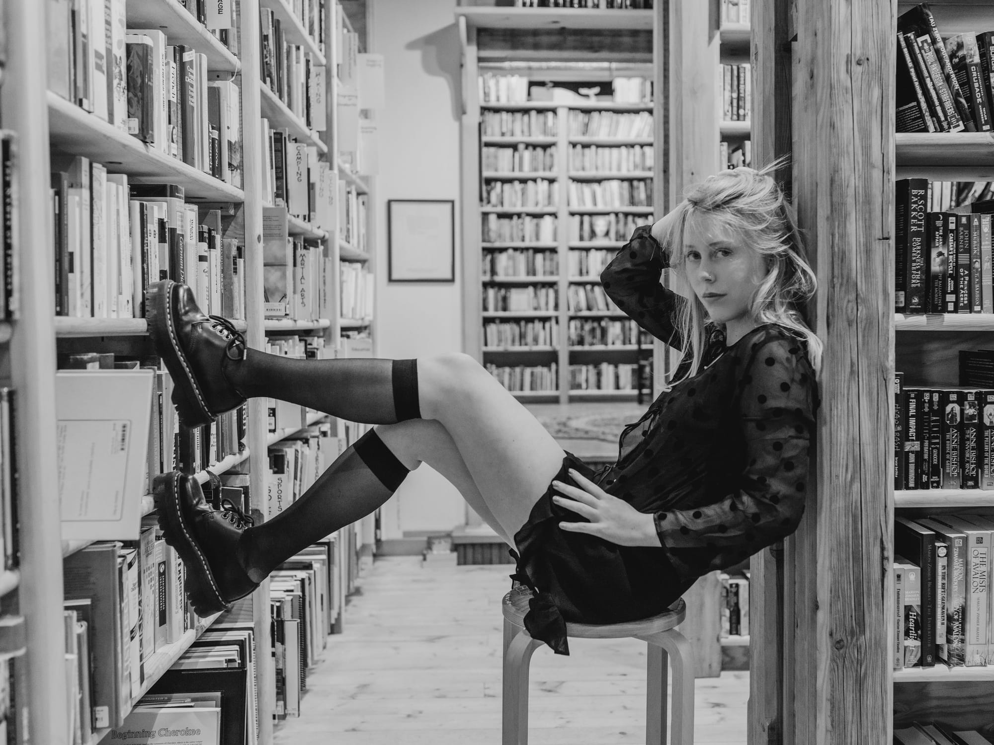 Black and white portrait of a young woman in a bookstore