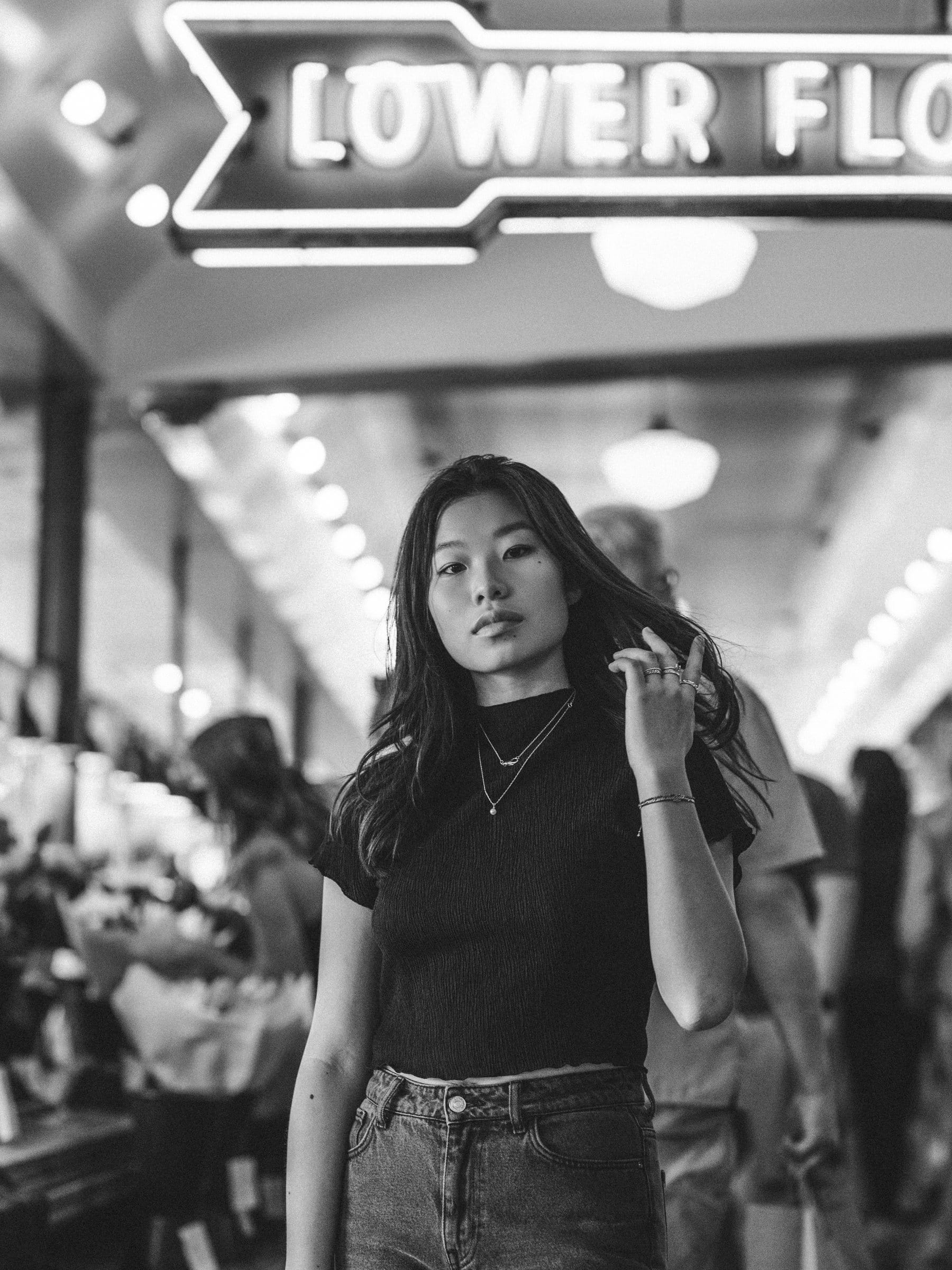 Black and white portrait of a young woman under a market sign