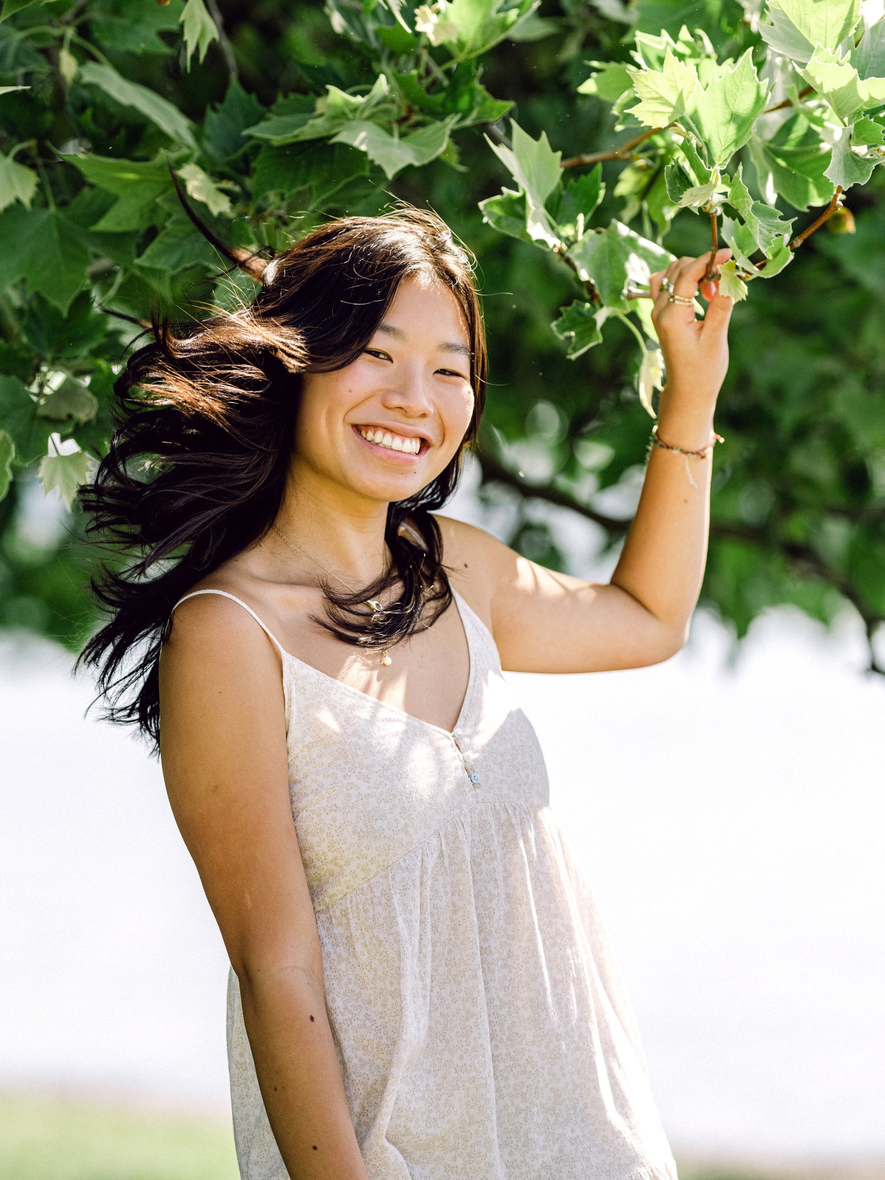 Young woman laughing under green leaves