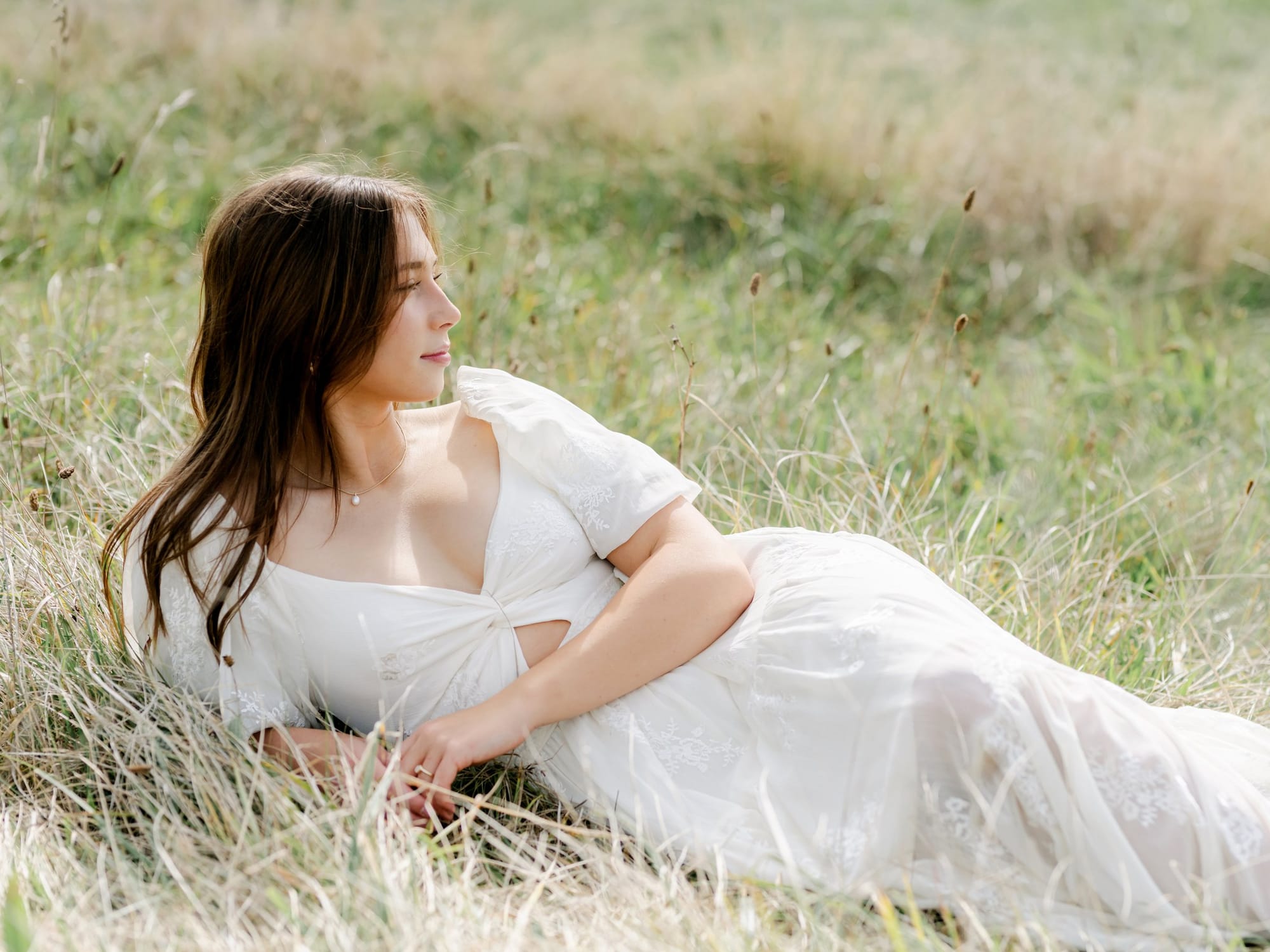 Young woman in white lying in tall grass