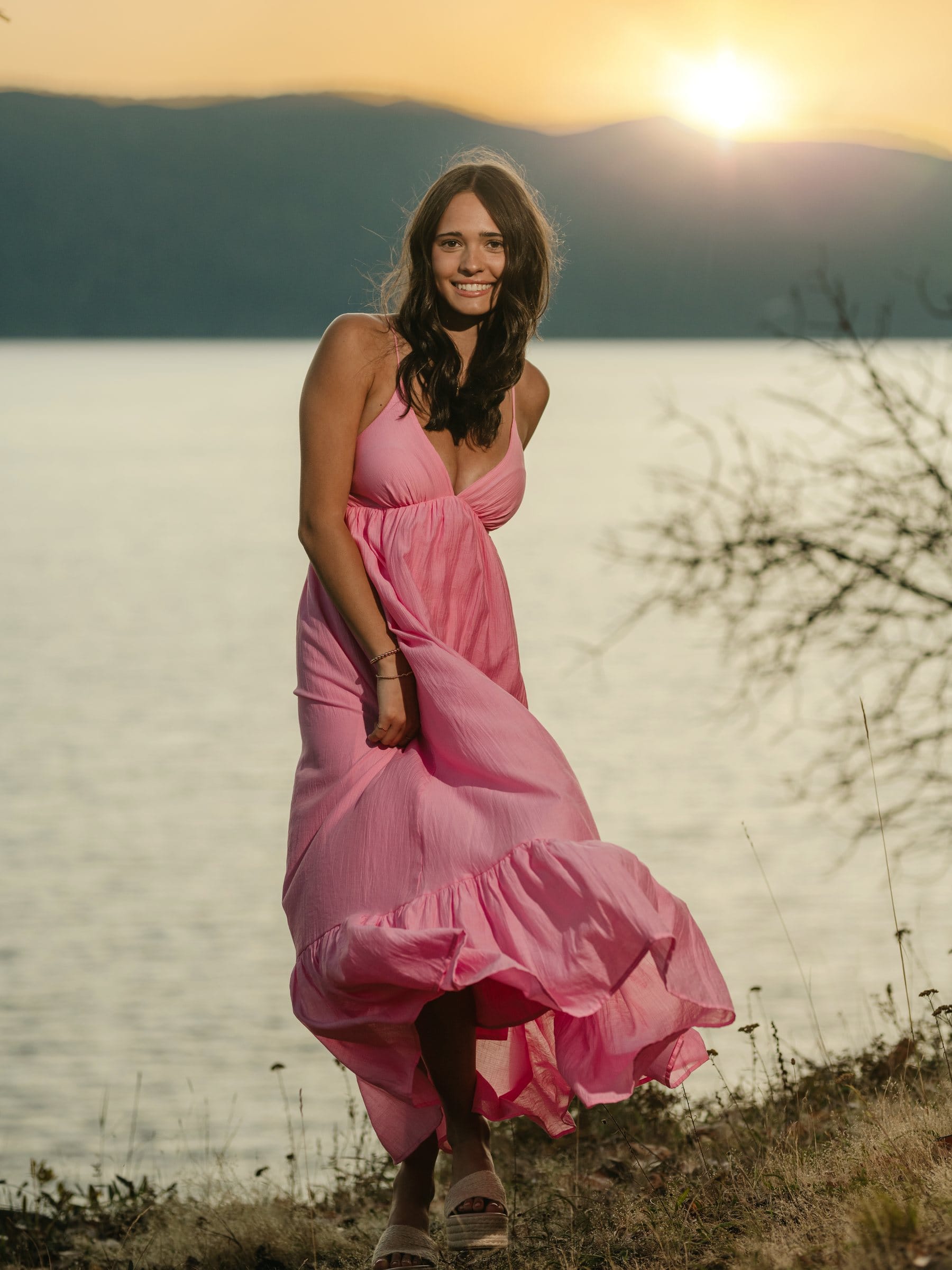 Young woman in a flowing pink dress at sunset by the water