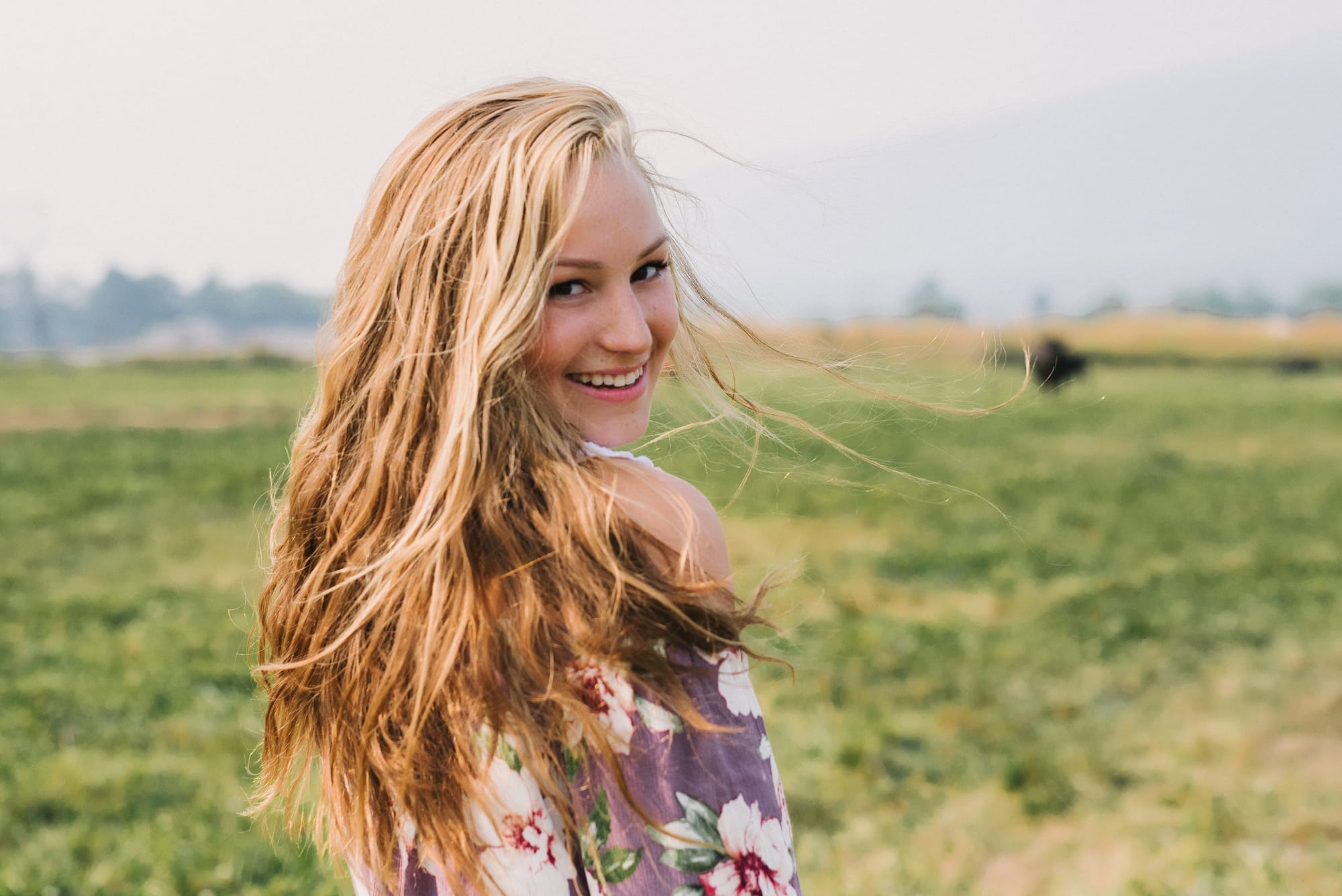 Smiling young woman with windswept hair in a meadow