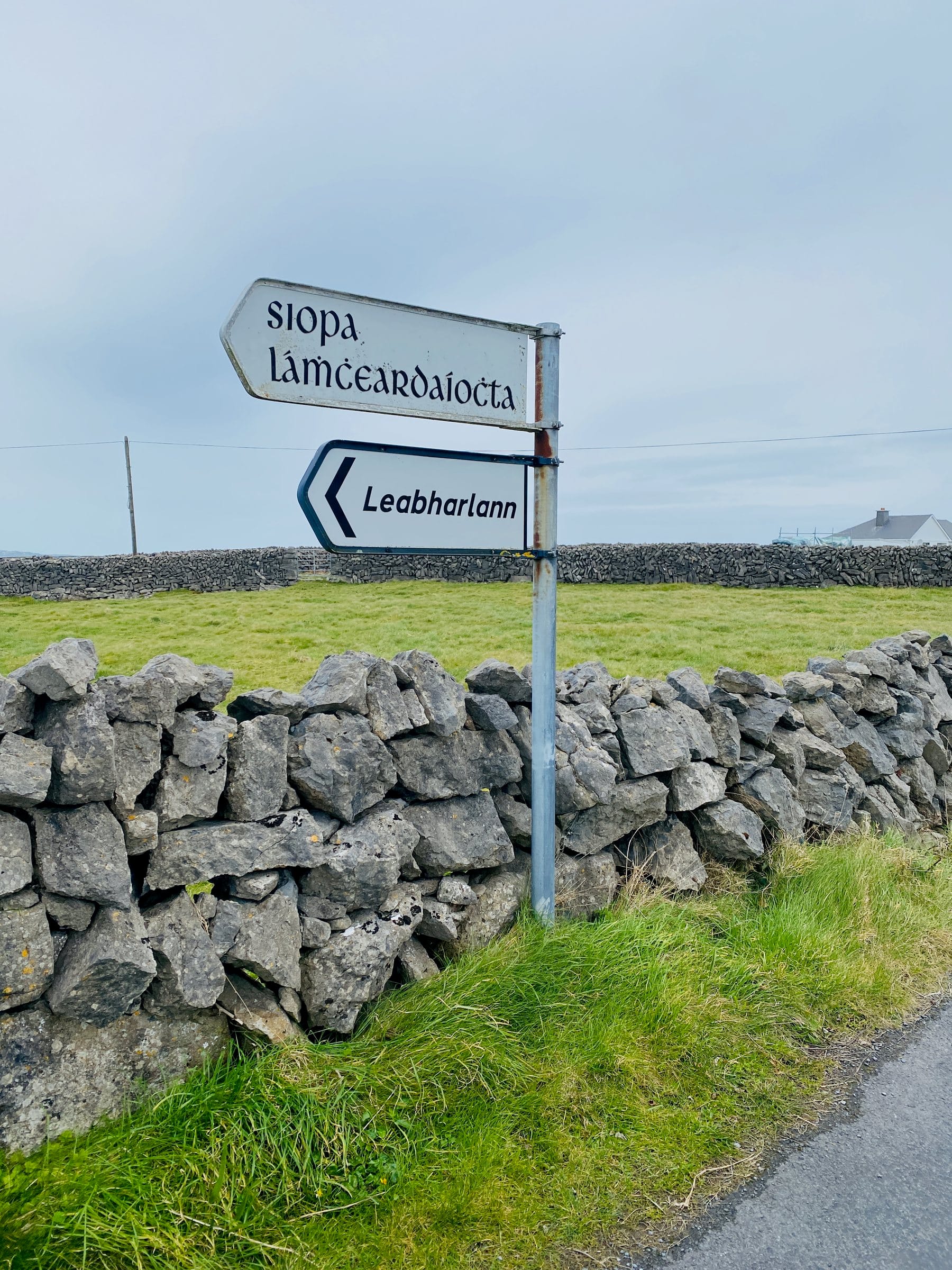 Gaelic signposts beside a stone wall in Ireland