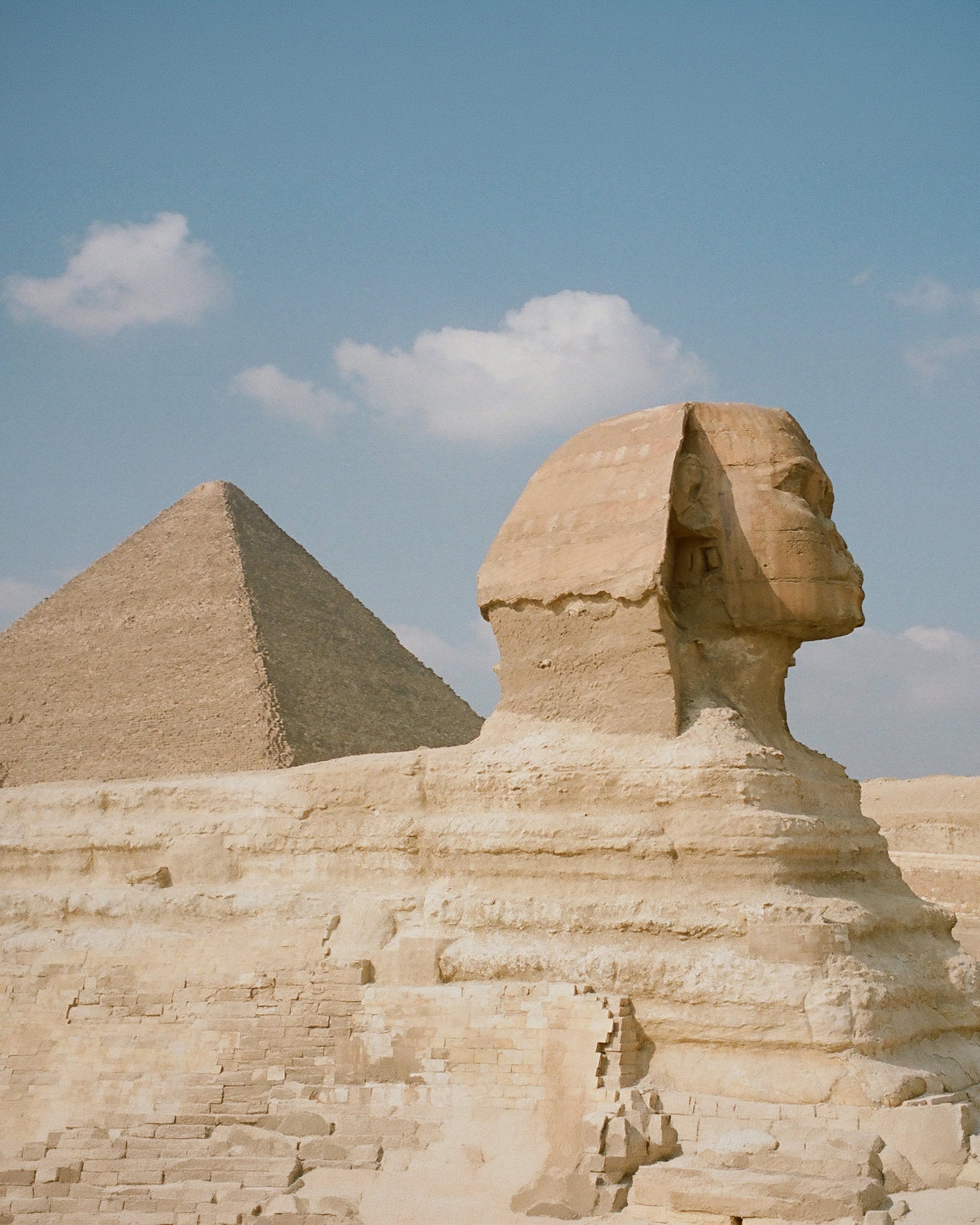 The Sphinx and a pyramid under a blue sky in Giza