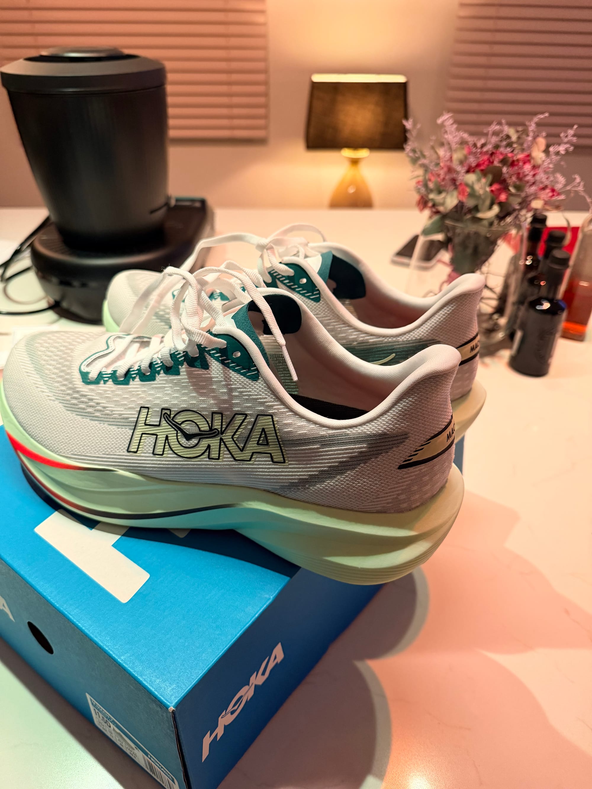 Hoka Mach 7 coloris frost / yuzu posées sur leur boîte bleue Hoka, vue latérale montrant le mesh jacquard et la semelle EVA supercritique