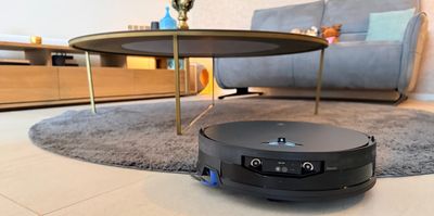 Ecovacs X12 OmniCyclone en action dans le salon entre le tapis et la table basse, capteurs FocusJet et caméra visibles à l'avant