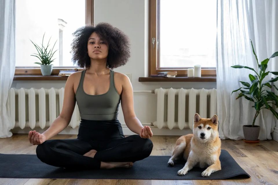 Une fille métisse médite sur un tapis de méditation avec un chien à sa droite