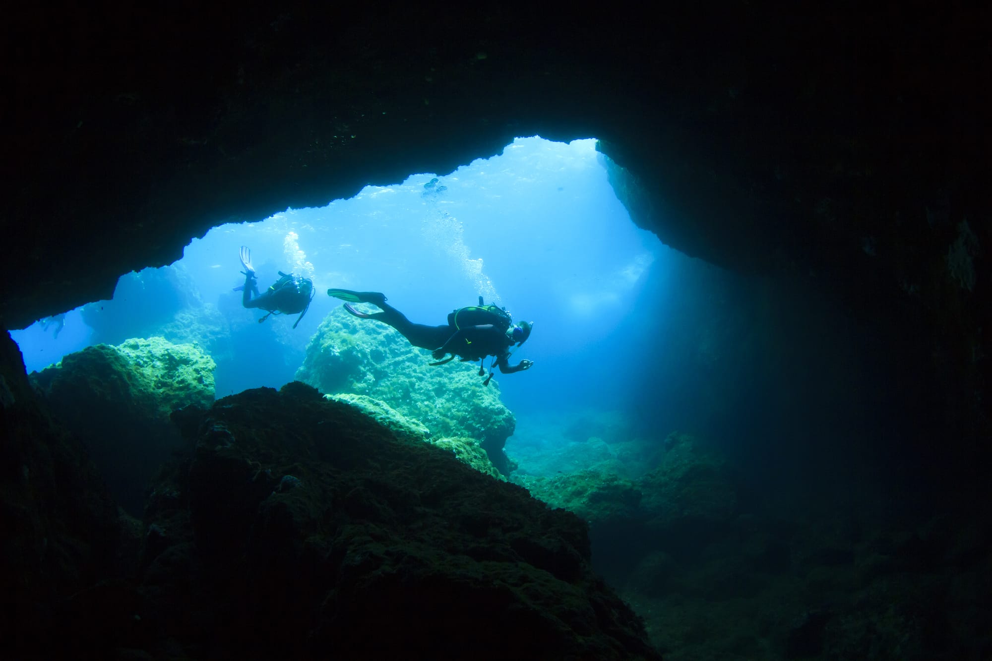 Two divers coming in an underwater cavern