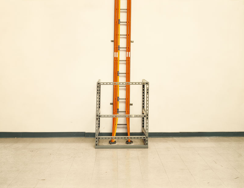 Transatlantic Submarine Cables Reaching Land<br>VSNL International, Avon, N.J.<br /><br />
These VSNL submarine telecommunications cables extend 8,037.4 miles across the Atlantic Ocean. Capable of transmitting over 60 million simultaneous voice conversations, these underwater fiber-optic cables stretch from Saunton Sands in the United Kingdom to the coast of New Jersey. The cables run below ground and emerge directly into the VSNL International headquarters, where signals are amplified and split into distinctive wavelengths enabling transatlantic phone calls and internet transmissions.<br /><br />
Underwater fiber-optic cables are laid along the ocean’s floor by specially designed ships. Cables are buried as they approach shore and armored to protect against undersea landslides, marine life (sharks, in particular), and fishing equipment. Fishermen are advised of cable locations as hooking one can interfere with international communication services as well as sink a boat.<br /><br />
VSNL operates one of 14 submarine cable systems connected to the continental United States. Exchanges originating in the U.S. are combined and enhanced before broadcast and transmission across the Atlantic. As of 2005, submarine cables link all the world’s continents except Antarctica.
