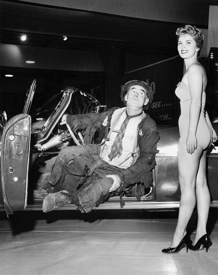 A model wears a nude-colored swimsuit for a skit with an Emmett Kelly-inspired hobo to promote Chrysler at the 1960 Detroit Auto Show.