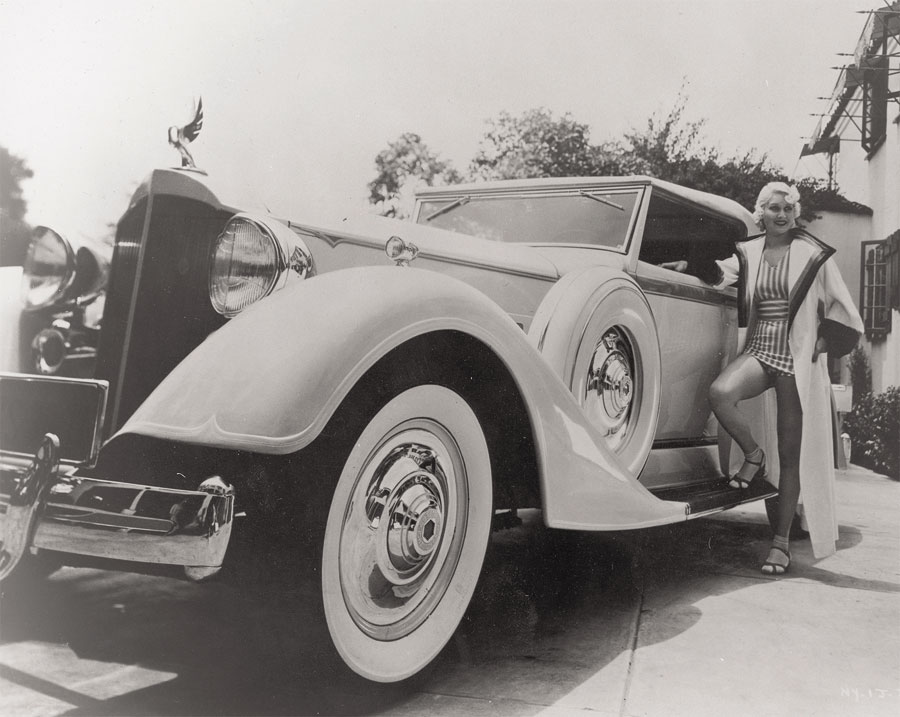 Hazel Forbes, star of <i>Down to their Last Yacht</i> and <i>Bachelor Bait</i>, lends her bathing suit-clad image to a 1934 Packard Super Eight Convertible Victoria.