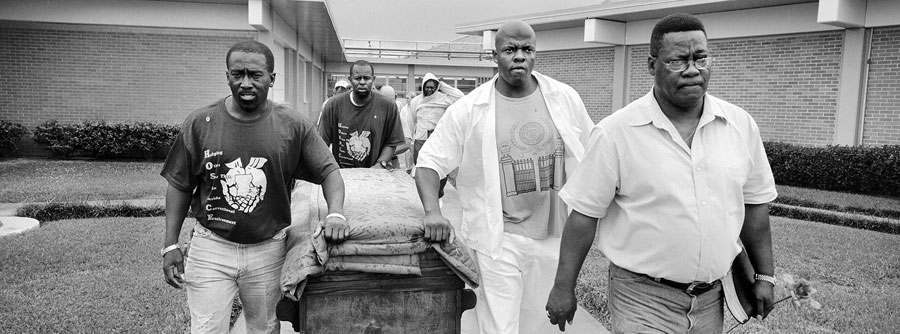 Hospice volunteers roll George Alexander's coffin from the prison hospital to an ambulance where it will be driven to meet the hand-carved wooden hearse and the procession of mourners. 