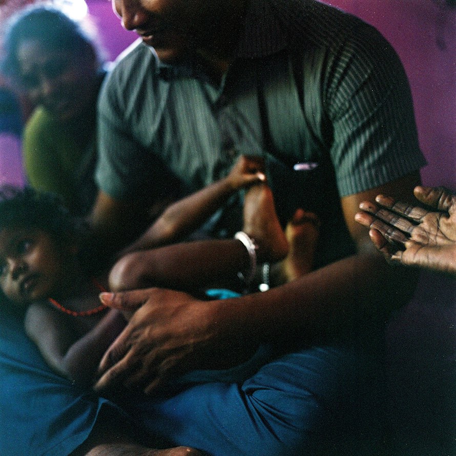 Mohana holds her niece while sitting with her family in their house in the village of Devanapattinam. November 2013.