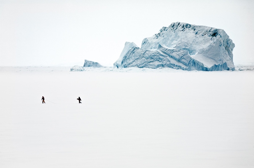“After two days of our ship shoved into the sea ice during a blind blizzard, the weather finally cleared. It was safe enough to allow two expedition staff members roped to each other to test the thickness of the sea ice. On the ice, they laid a path for the passengers to reach the massive icebergs and visit a nearby emperor penguin colony.” Walking on the Frozen Sea Ice, Cape Washington, Antarctica, December 2006.
