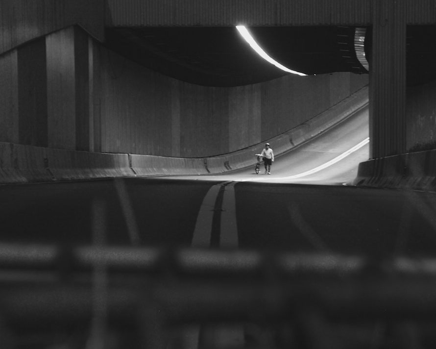 A lone cyclist jumps over a barricade and strolls through an empty traffic tunnel. A single figure is rare to see during the revolution.