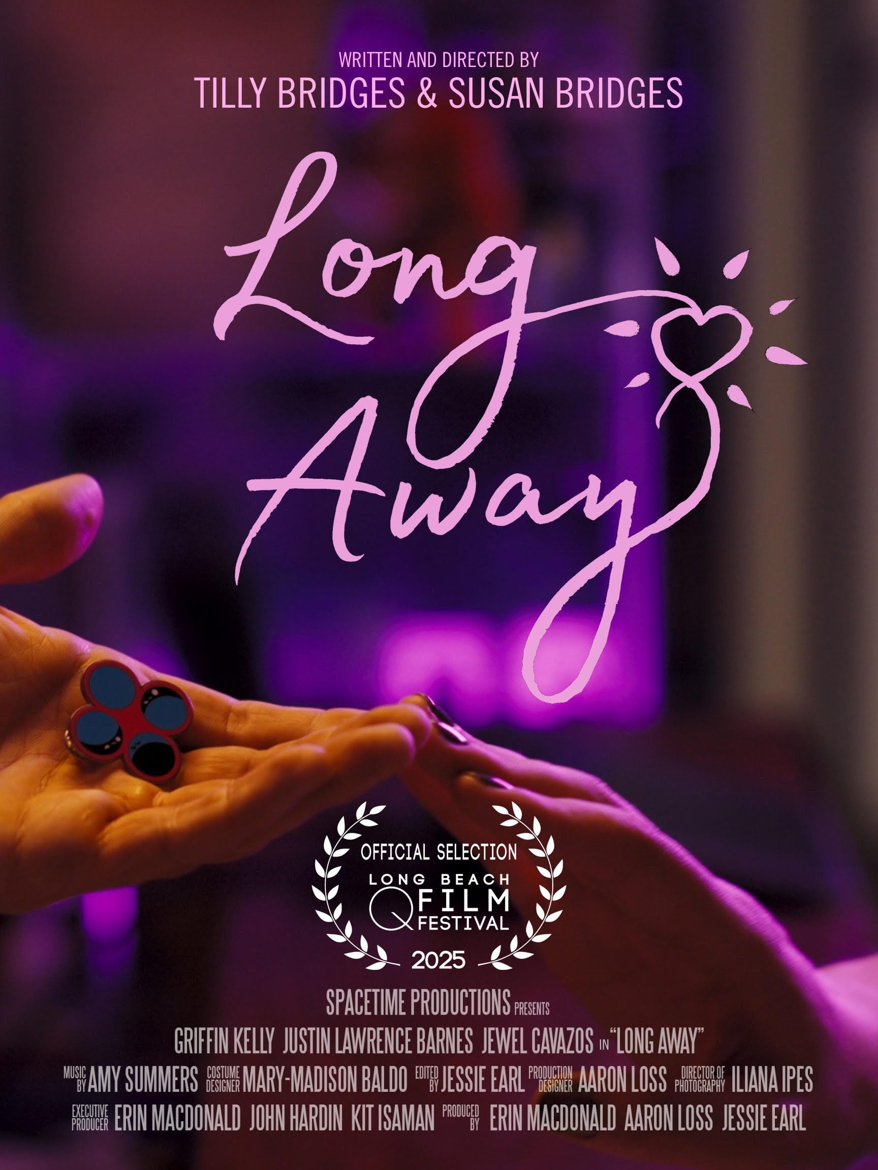 one hand reaching out, palm upward, holding an enamel pin displaying four circles, and another hand reaching out, palm downward, the two hands touch at the fingertips and are bathed in pink light. text reads: LONG AWAY WRITTEN AND DIRECTED BY TILLY BRIDGES & SUSAN BRIDGES SPACETIME PRODUCTIONS PRESENTS GRIFFIN KELLY JUSTIN LAWRENCE BARNES JEWEL CAVAZOS in “LONG AWAY” MUSIC BY AMY SUMMERS COSTUME DESIGN MARY-MADISON BALDO EDITED BY JESSIE EARL PRODUCTION DESIGNER AARON LOSS DIRECTOR OF PHOTOGRAPHY ILIANA IPES EXECUTIVE PRODUCER ERIN MACDONALD JOHN HARDIN KIT ISAMAN PRODUCED BY ERIN MACDONALD AARON LOSS JESSIE EARL official selection Long Beach QFilm Festival 2025