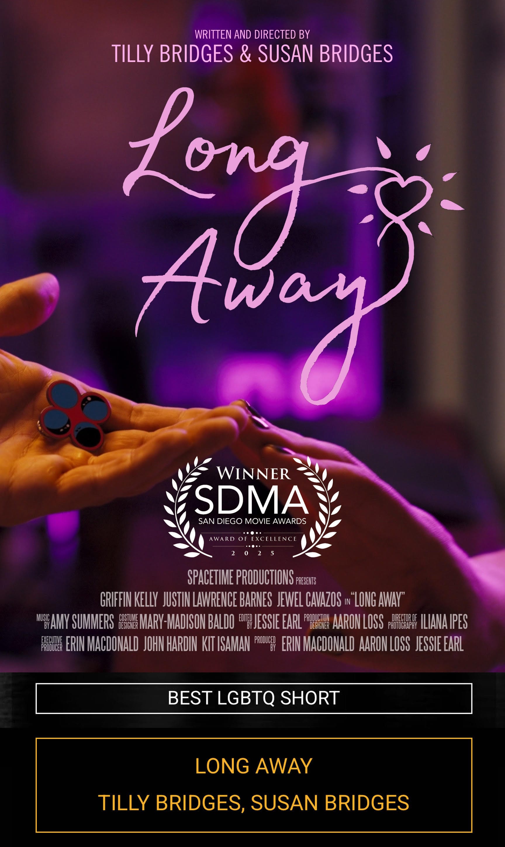 one hand reaching out, palm upward, holding an enamel pin displaying four circles, and another hand reaching out, palm downward, the two hands touch at the fingertips and are bathed in pink light. text reads: LONG AWAY WRITTEN AND DIRECTED BY TILLY BRIDGES & SUSAN BRIDGES SPACETIME PRODUCTIONS PRESENTS GRIFFIN KELLY JUSTIN LAWRENCE BARNES JEWEL CAVAZOS in “LONG AWAY” MUSIC BY AMY SUMMERS COSTUME DESIGN MARY-MADISON BALDO EDITED BY JESSIE EARL PRODUCTION DESIGNER AARON LOSS DIRECTOR OF PHOTOGRAPHY ILIANA IPES EXECUTIVE PRODUCER ERIN MACDONALD JOHN HARDIN KIT ISAMAN PRODUCED BY ERIN MACDONALD AARON LOSS JESSIE EARL winner San Diego Movie Awards, Award of Excellence, 2025. Best LGBTQ short, LONG AWAY, Tilly Bridge, Susan Bridges