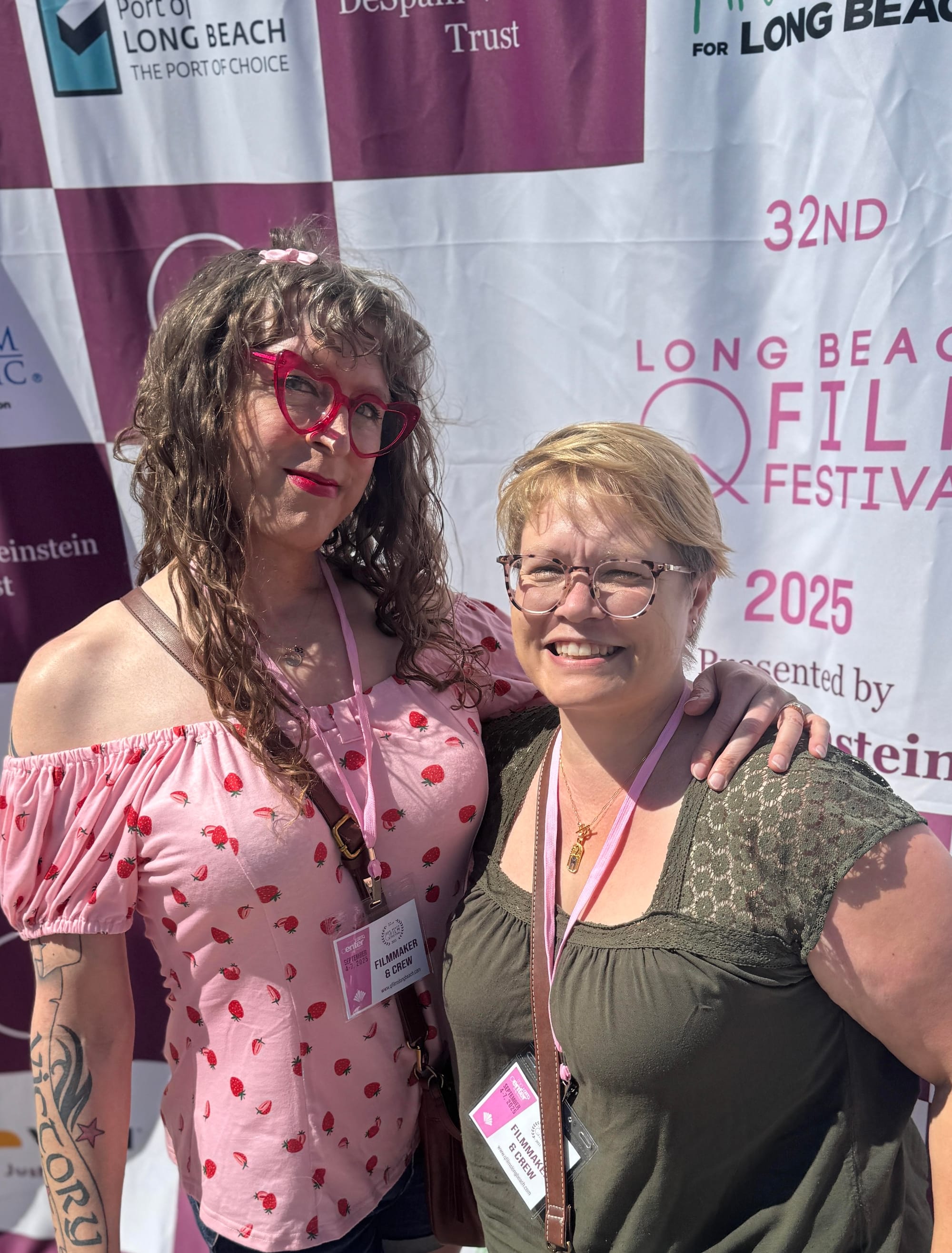 Tilly and Susan in front of the 32nd Annual Long Beach QFilm Festival step and repeat, with the sun shining right in our eyes because Sol is queerphobic, I guess