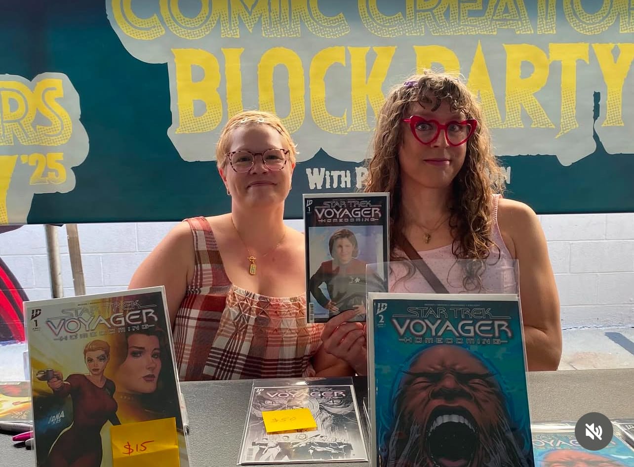 Us signing at Revenge Of’s Comic Creator Block Party, holding up a copy of Star Trek Voyager Homecoming issue 1