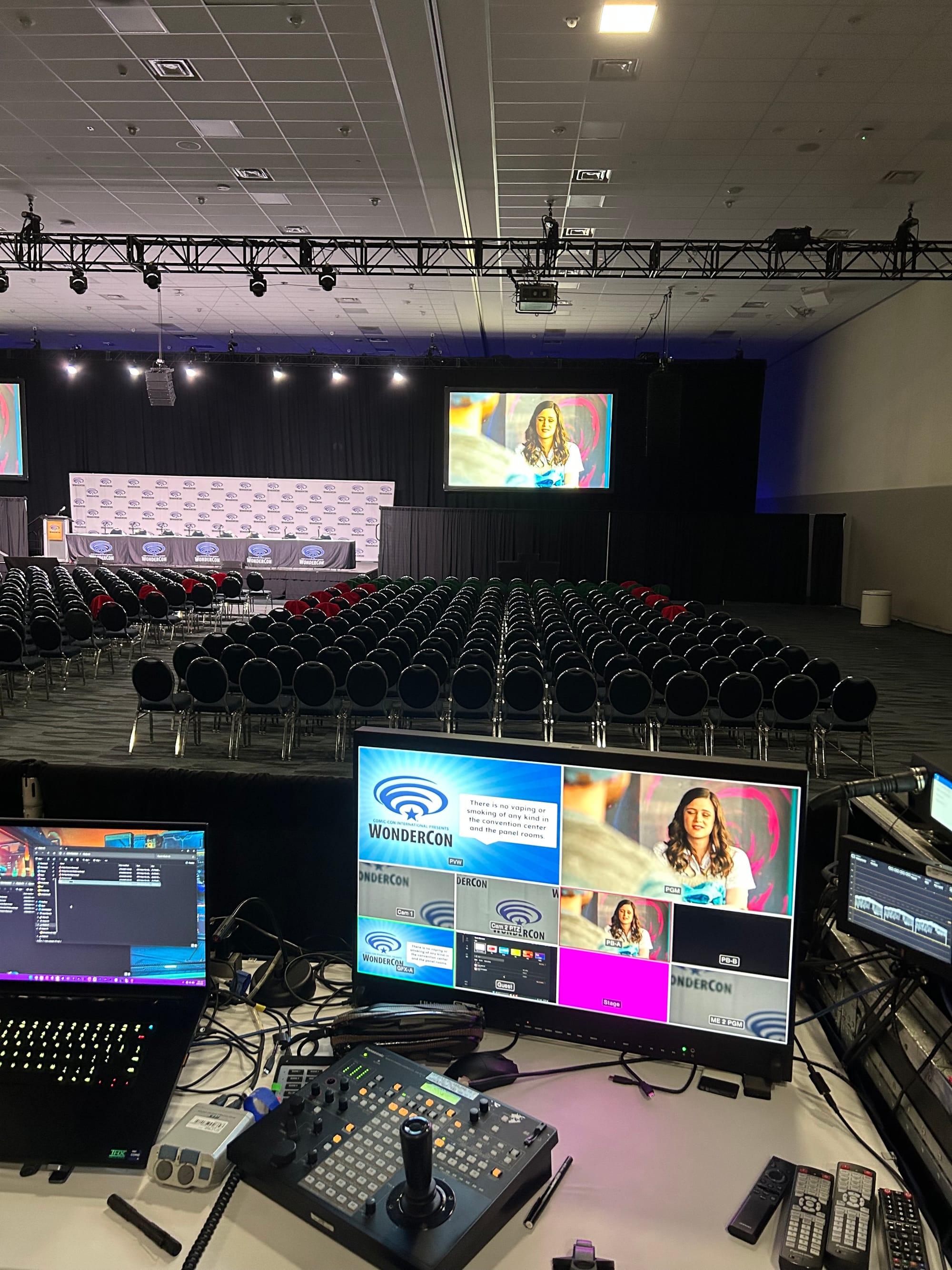 Long Away seen on screen with many other video feeds in the panel control booth, and also seen on one of the big screens hanging at the front of the expansive panel room