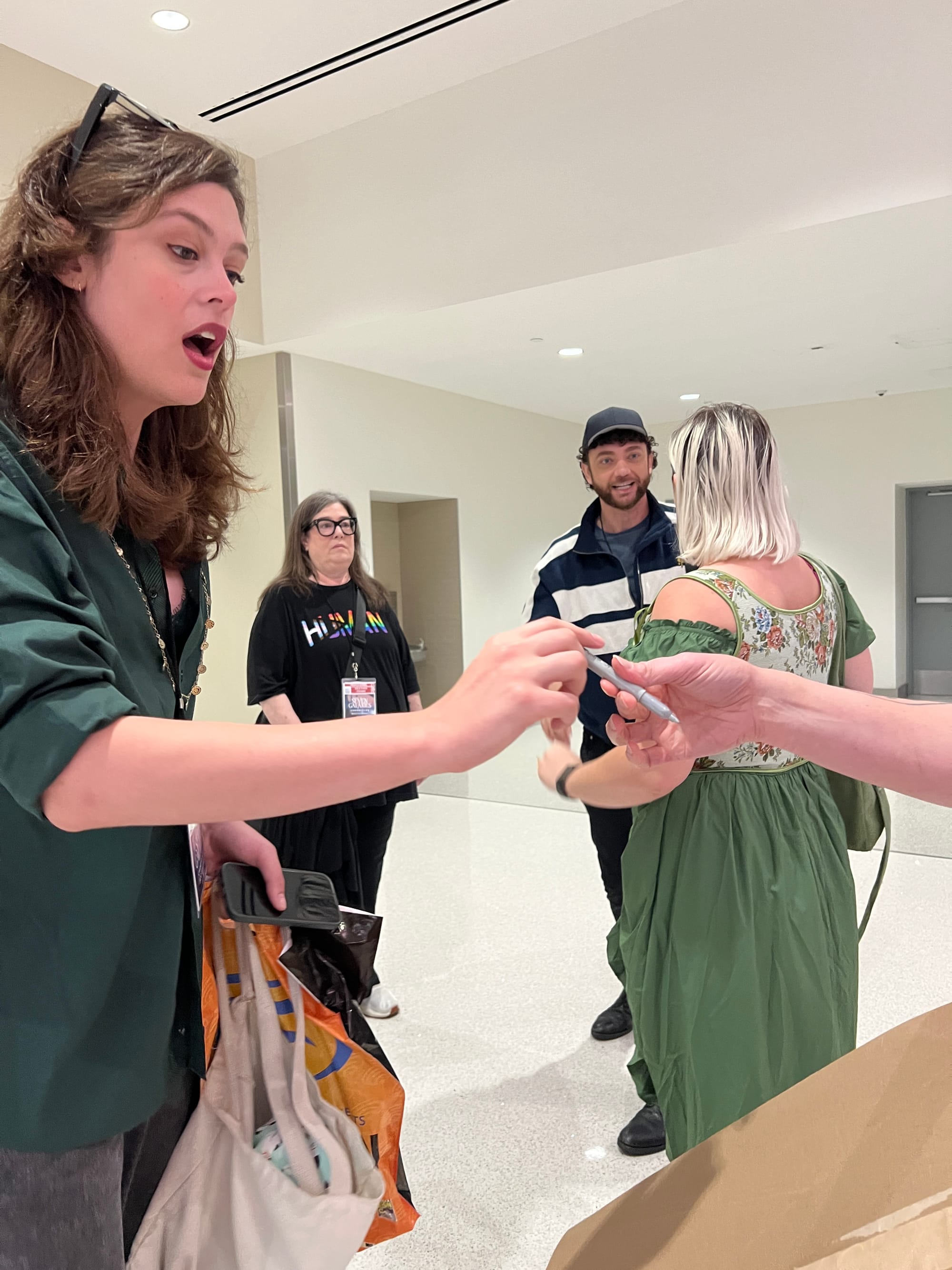Tilly handing a silver sharpie to Griffin Kelly, who looks surprised