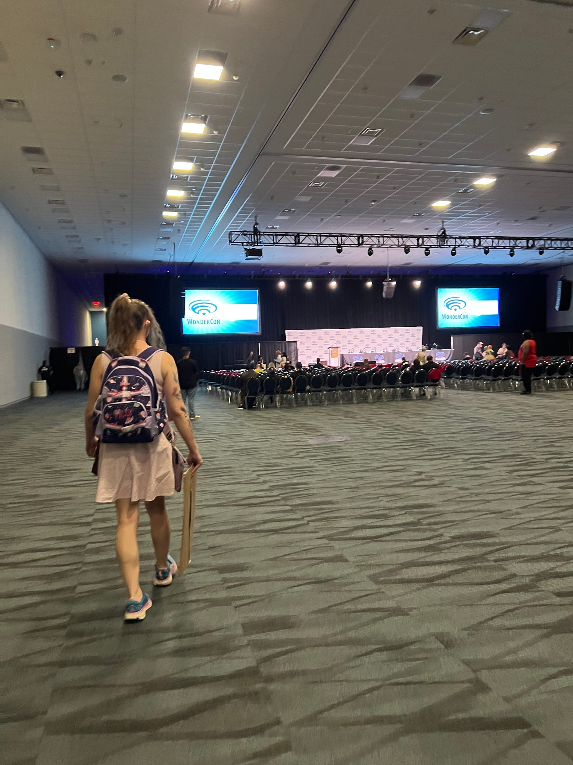 Tilly walking in to the very large panel room, with two large screens on either side of the table for panelists