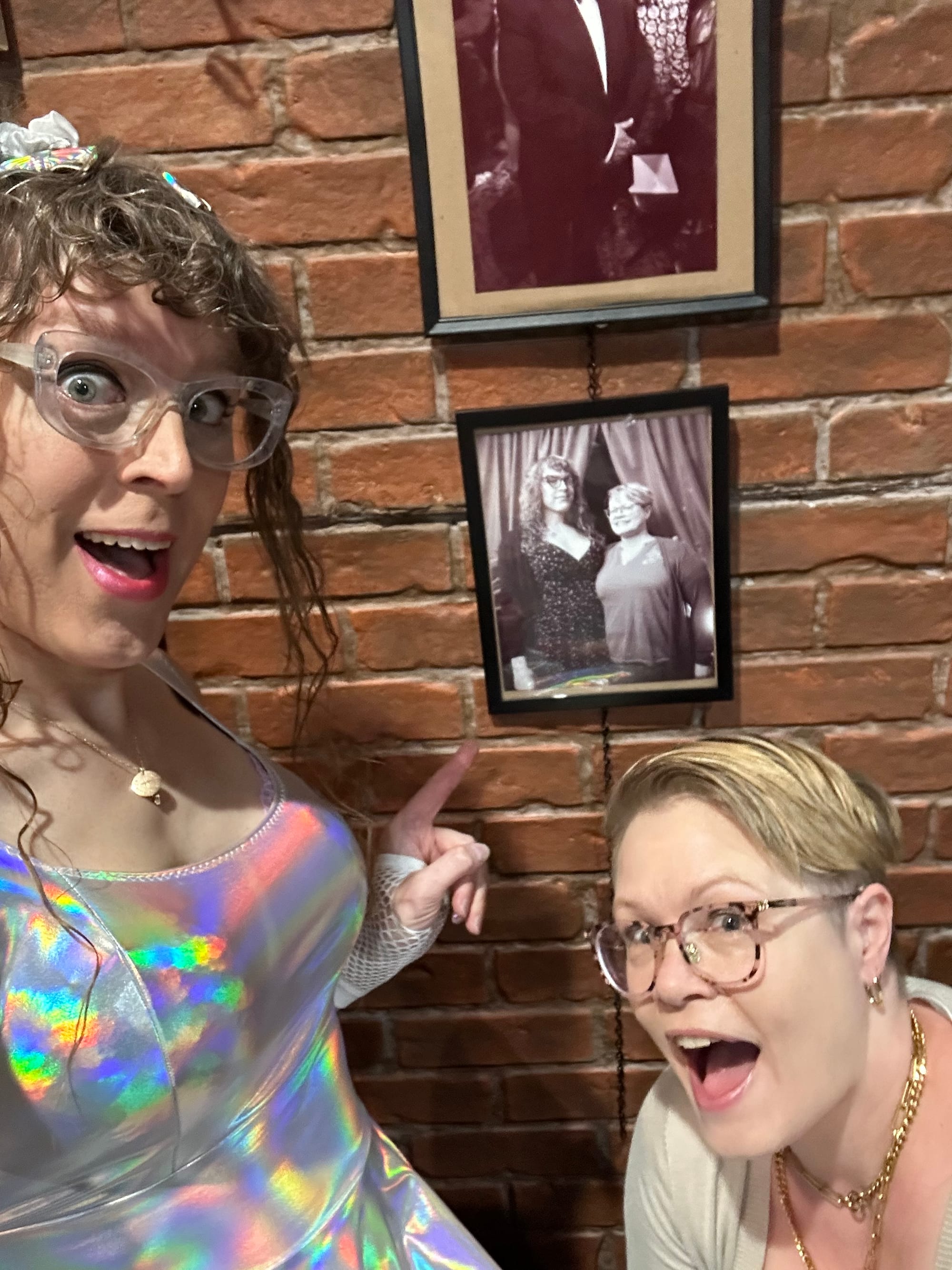 Us smiling and pointing to a framed photo of us on the wall.