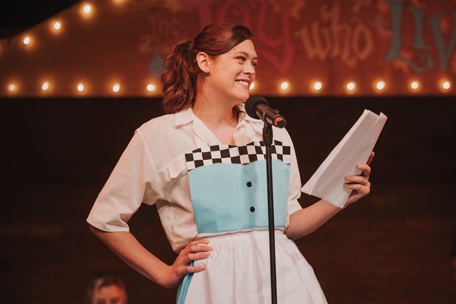 Griffin Kelly as Harper, forcing a smile