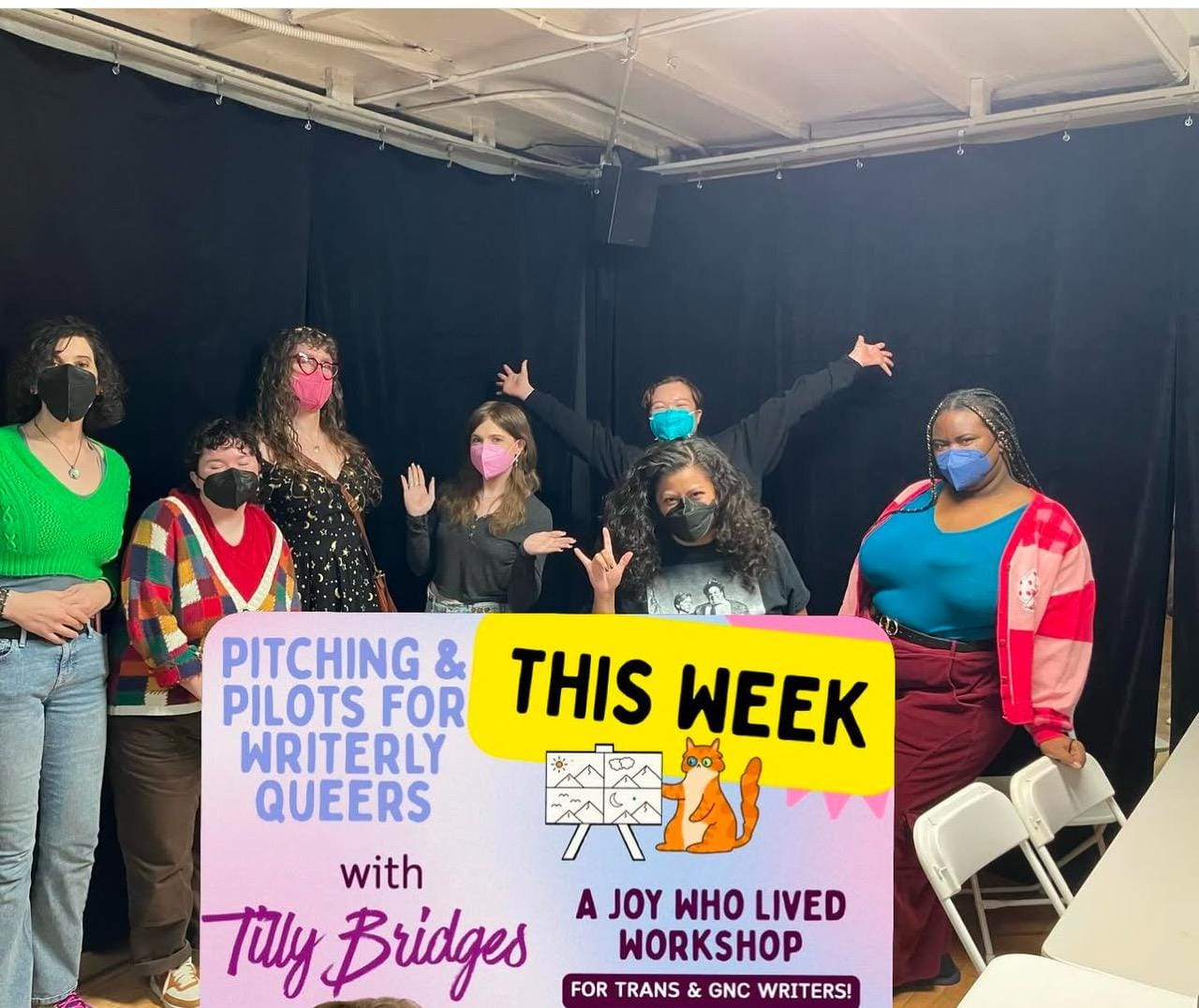 A photo of tilly with six of the attendees of her pitching and pilots workshop, in the corner of a room in front of black curtains