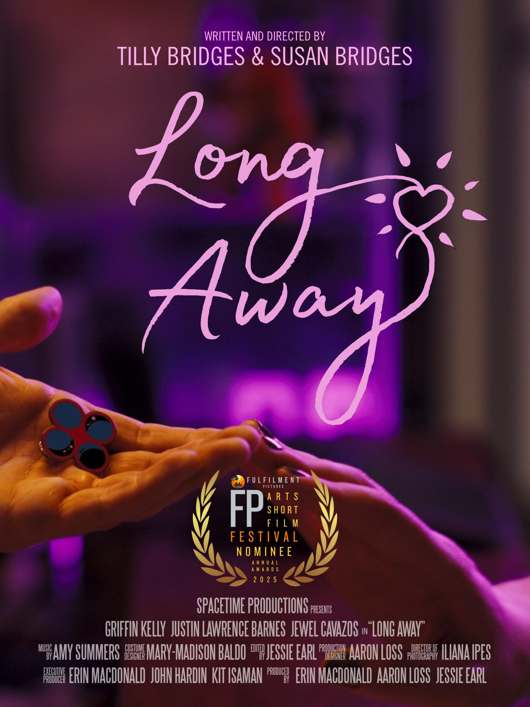 one hand reaching out, palm upward, holding an enamel pin displaying four circles, and another hand reaching out, palm downward, the two hands touch at the fingertips and are bathed in pink light. text reads: LONG AWAY WRITTEN AND DIRECTED BY TILLY BRIDGES & SUSAN BRIDGES SPACETIME PRODUCTIONS PRESENTS GRIFFIN KELLY JUSTIN LAWRENCE BARNES JEWEL CAVAZOS in “LONG AWAY” MUSIC BY AMY SUMMERS COSTUME DESIGN MARY-MADISON BALDO EDITED BY JESSIE EARL PRODUCTION DESIGNER AARON LOSS DIRECTOR OF PHOTOGRAPHY ILIANA IPES EXECUTIVE PRODUCER ERIN MACDONALD JOHN HARDIN KIT ISAMAN PRODUCED BY ERIN MACDONALD AARON LOSS JESSIE EARL FP Arts Short Film Festival Nominee 2025
