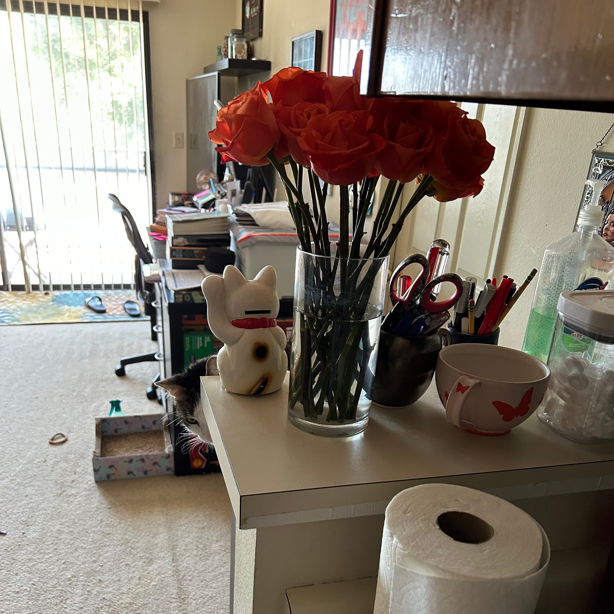 A vase of roses sitting on a countertop with part of our living room visible behind it.