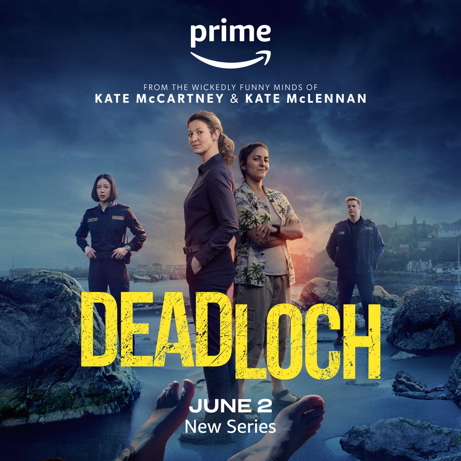 The cast of Deadlock standing on the rocky shores of a lake, under stormy skies, with the feet of a dead body in front of them