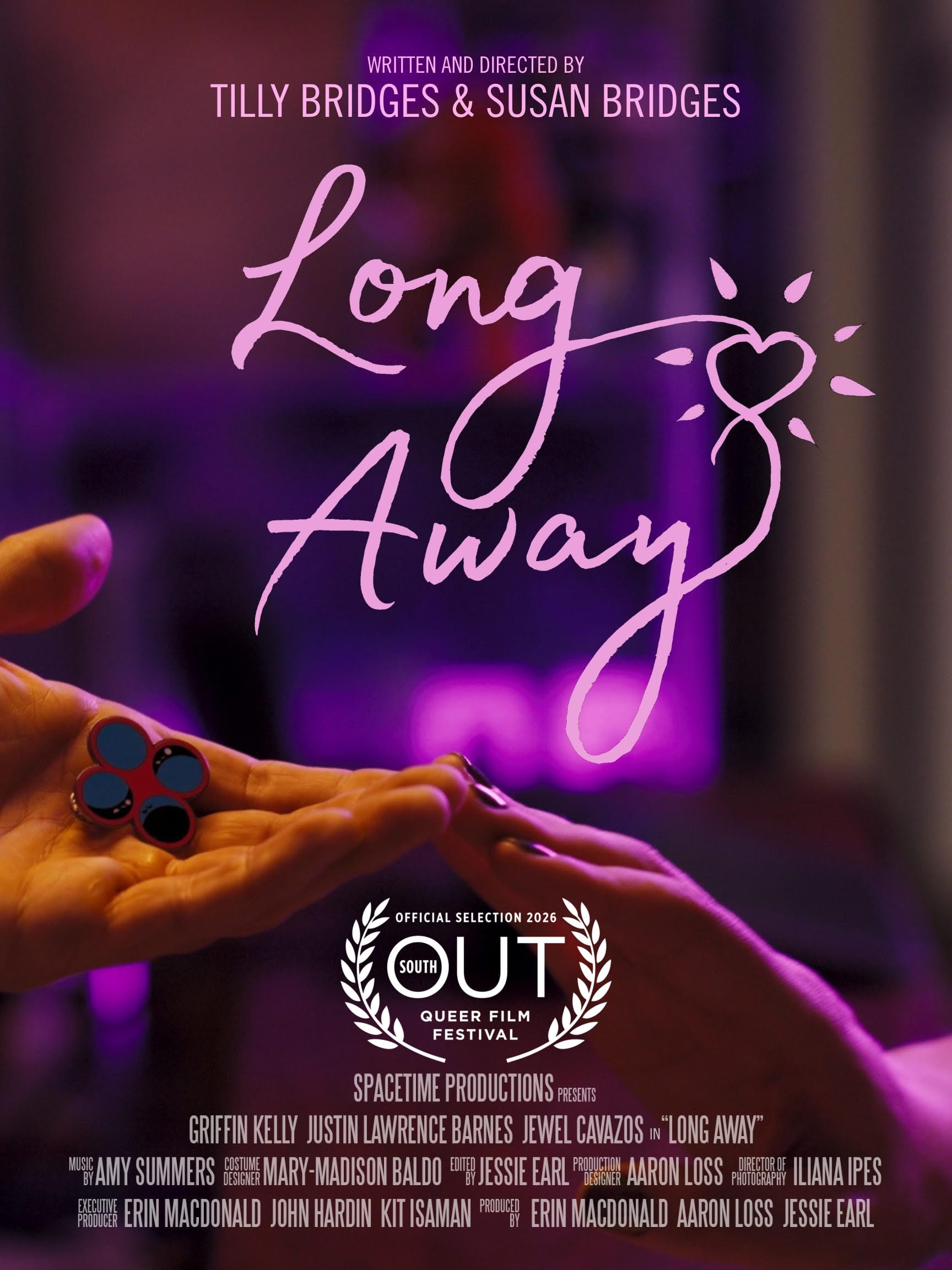 one hand reaching out, palm upward, holding an enamel pin displaying four circles, and another hand reaching out, palm downward, the two hands touch at the fingertips and are bathed in pink light. text reads: LONG AWAY WRITTEN AND DIRECTED BY TILLY BRIDGES & SUSAN BRIDGES SPACETIME PRODUCTIONS PRESENTS GRIFFIN KELLY JUSTIN LAWRENCE BARNES JEWEL CAVAZOS in “LONG AWAY” MUSIC BY AMY SUMMERS COSTUME DESIGN MARY-MADISON BALDO EDITED BY JESSIE EARL PRODUCTION DESIGNER AARON LOSS DIRECTOR OF PHOTOGRAPHY ILIANA IPES EXECUTIVE PRODUCER ERIN MACDONALD JOHN HARDIN KIT ISAMAN PRODUCED BY ERIN MACDONALD AARON LOSS JESSIE EARL Official Selection 2026 Out South queer film festival