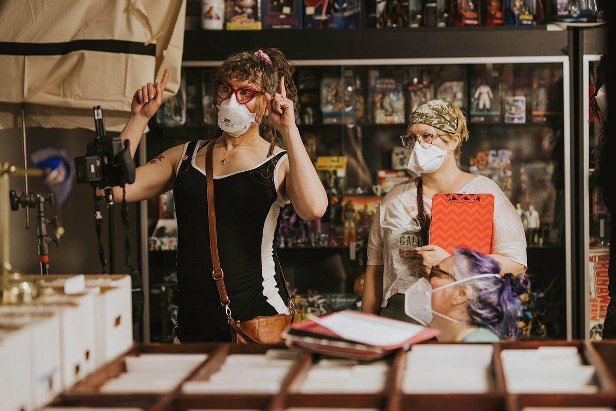 Tilly and Susan directing on the set of Long Away, inside a comic shop. For reasons unknown in both heaven and earth, Tilly is pointing upward with both hands. It’s a mystery!