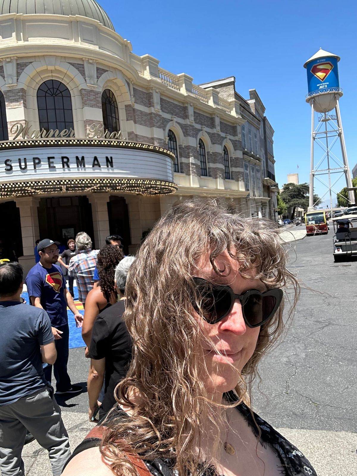 Tilly on the WB lot in front of their screening theater showing Superman, with the WB water tower wrapped in the Superman logo in the background