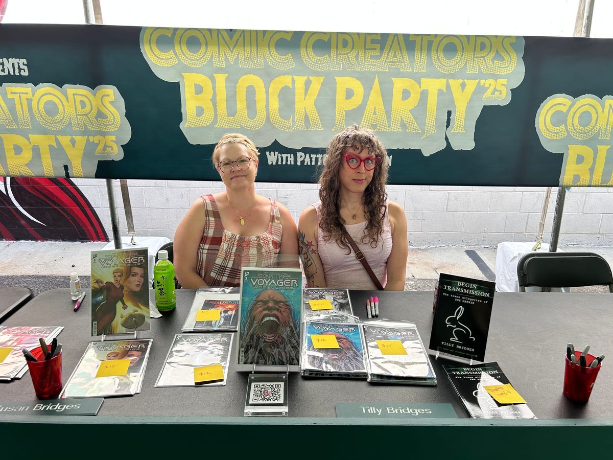 Us signing at our table at Revenge Of’s Comic Creator Block Party