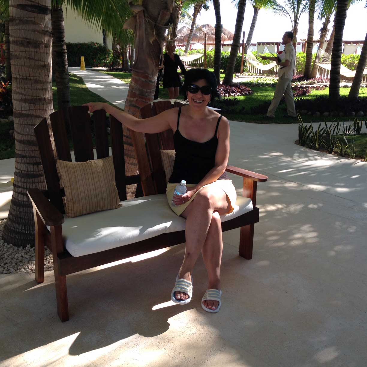 Sarah sitting on a bench at a tropical resort