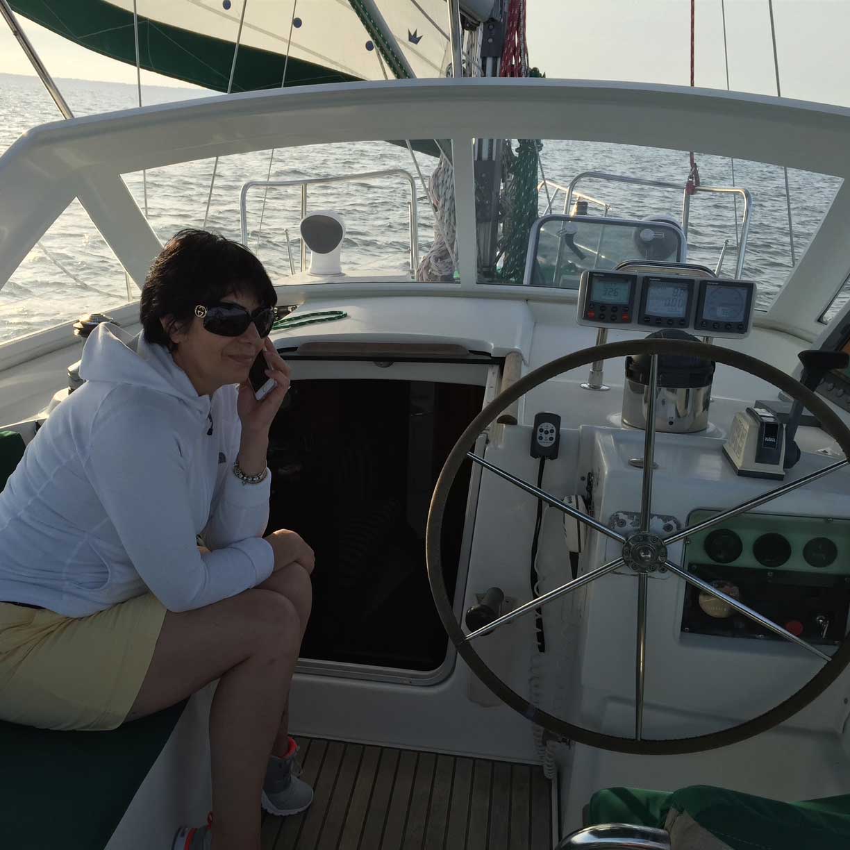Sarah sitting near the helm of a sailboat