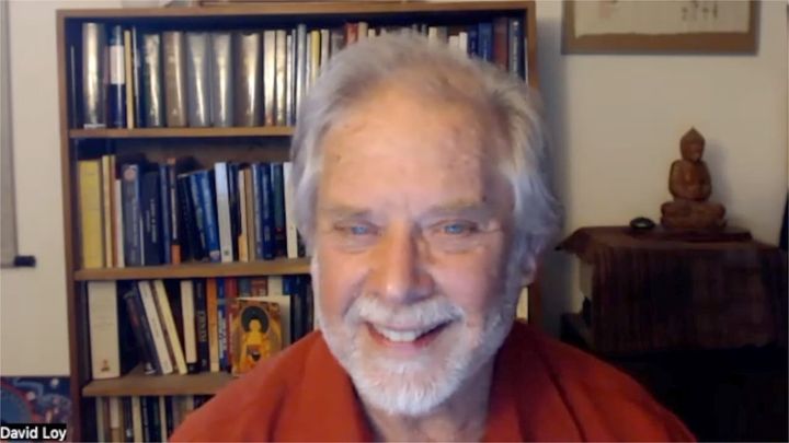 David Loy at home, with a bookshelf and Buddha figure in the backgroun