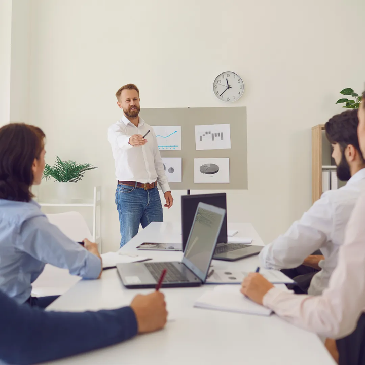Business professional presenting to a small team in a meeting room, illustrating leadership development and team engagement